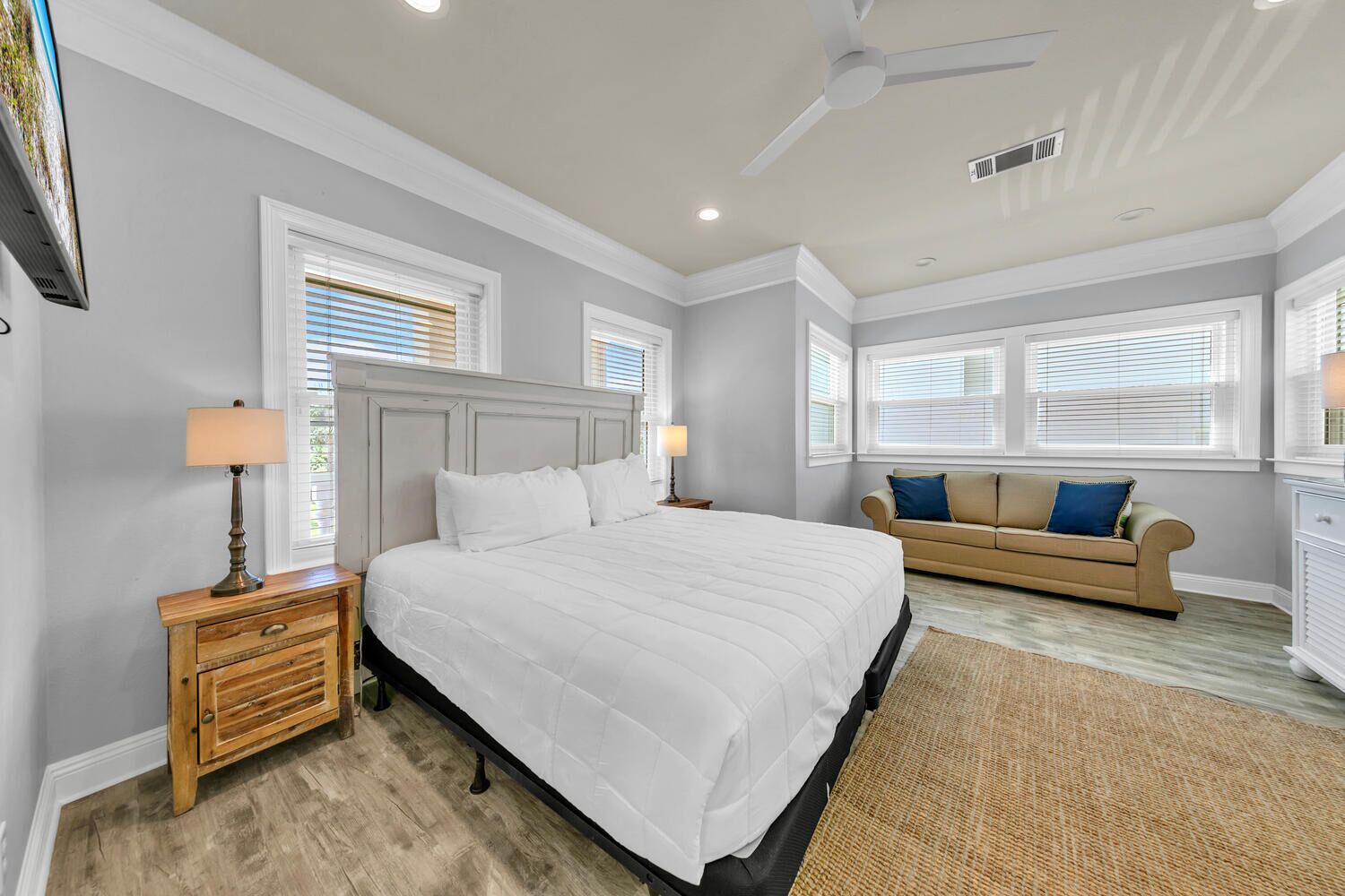 A bedroom with a bed, nightstands, a dresser, a ceiling fan, and a window with blinds.