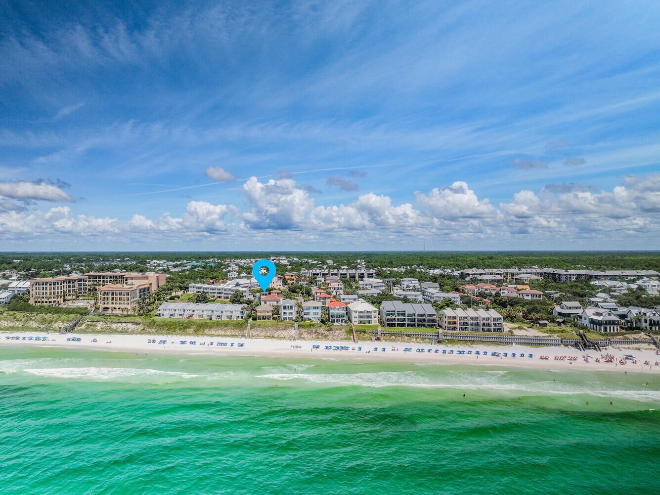 A coastal resort with beachfront properties, a sandy beach, and a clear view of the ocean.
