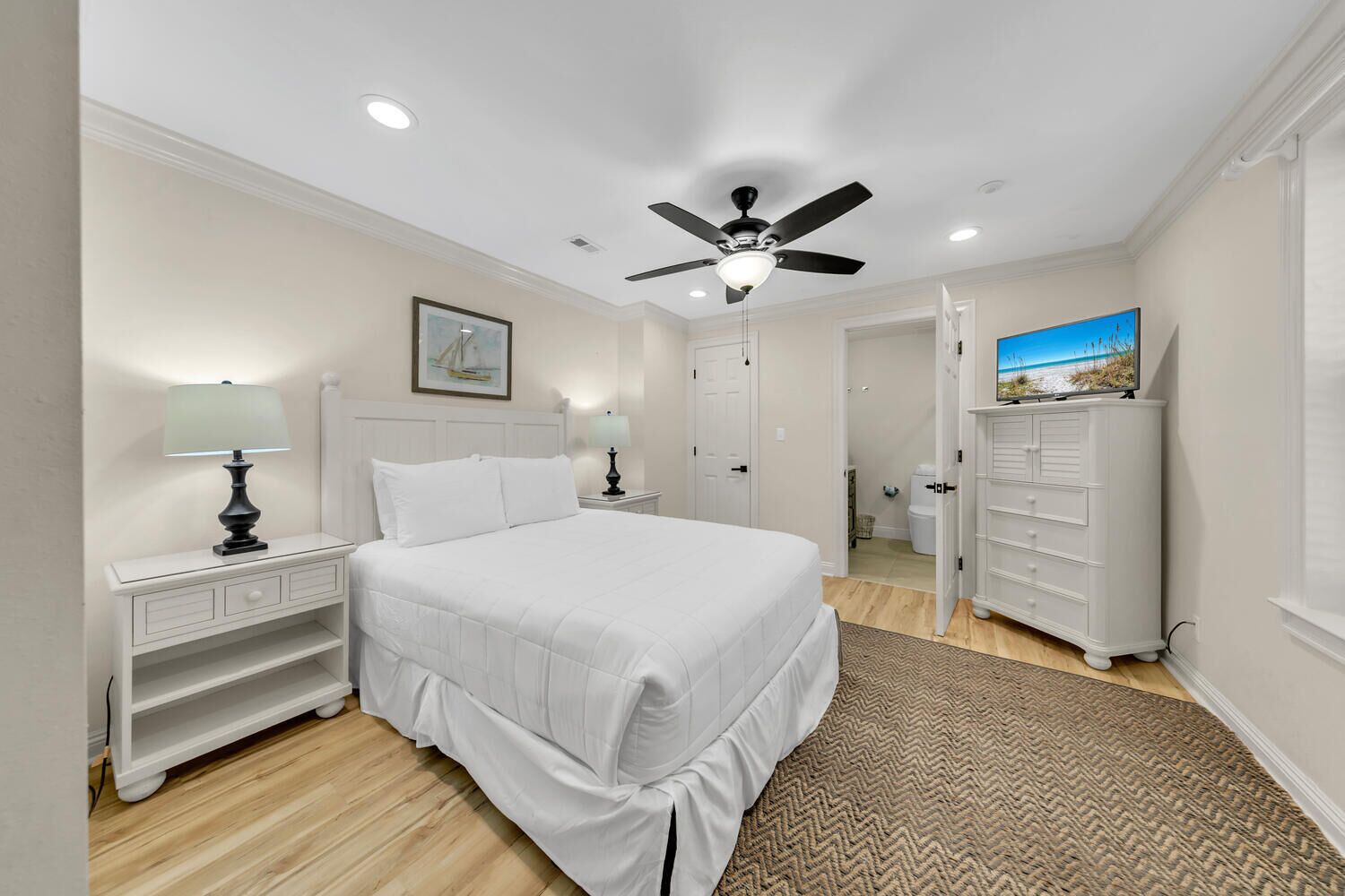 A bedroom with a bed, nightstands, a dresser, a ceiling fan, and a painting on the wall.
