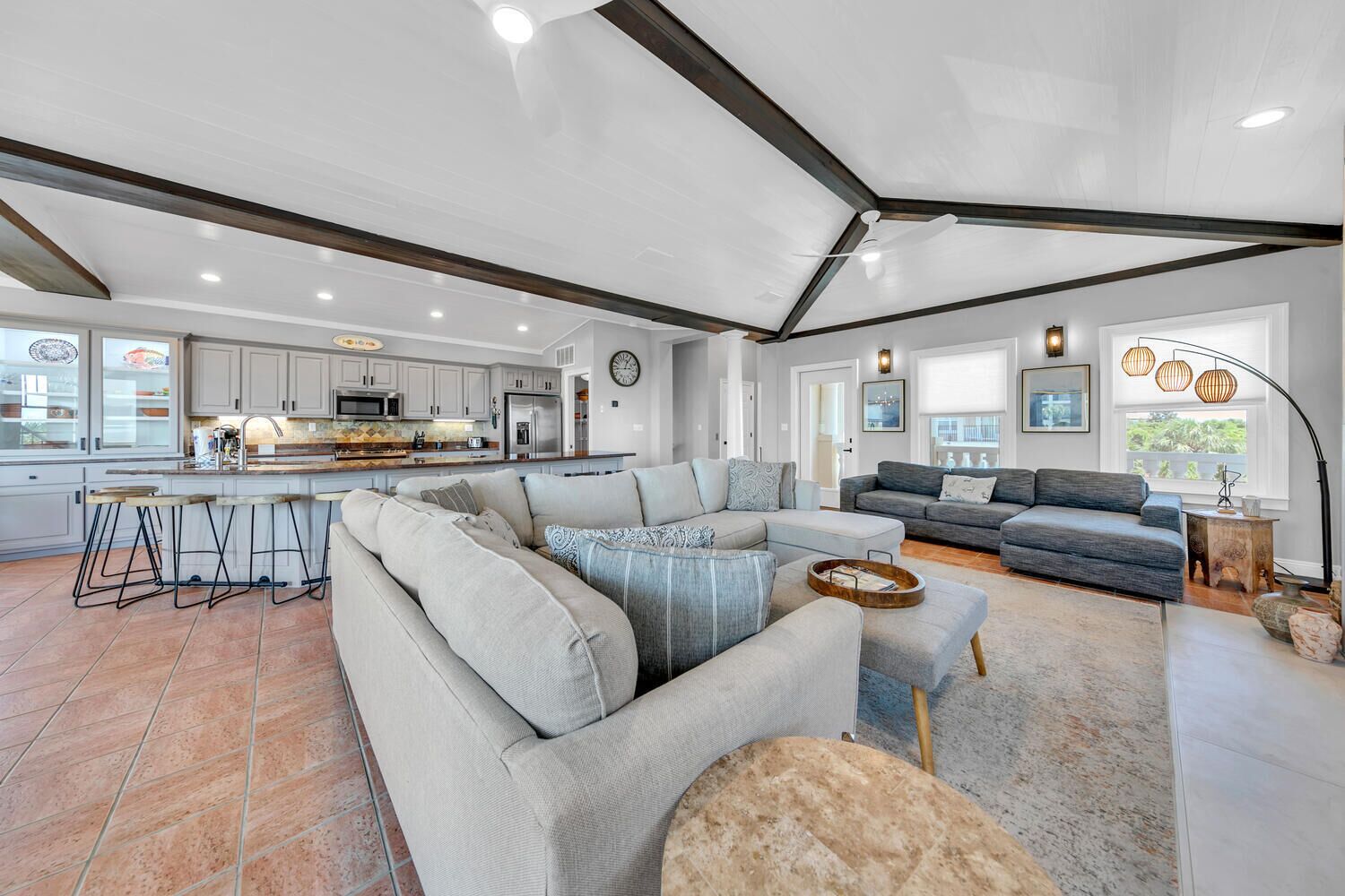 A spacious living area with a large sectional sofa, a dining area with bar stools, and a kitchen with modern appliances.