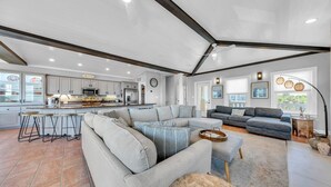 A spacious living area with a large sectional sofa, a dining area with bar stools, and a kitchen with modern appliances.