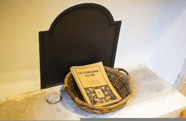 A book titled "LA TOSCANA fine '800" placed on a woven basket on a marble surface.