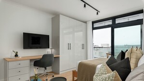 A modern bedroom with a bed, a desk, and a TV. - The Sage - Elegant Studio in Vibrant Sea Point (Cape Town)