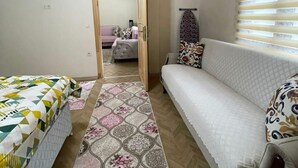 Un dormitorio con techo de madera, una cama con colcha estampada, un sofá con cojines estampados y una alfombra estampada.