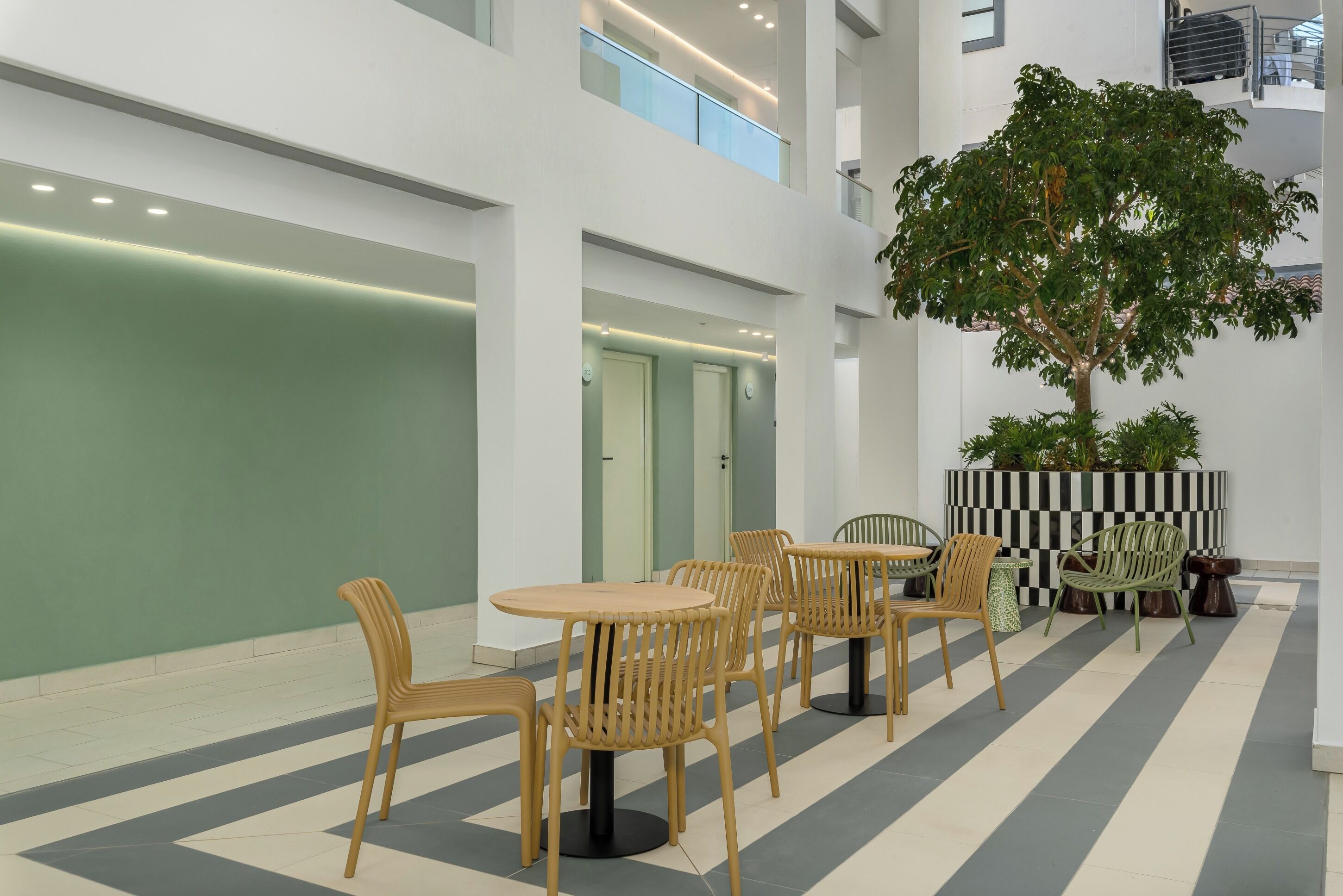 Un espacio interior moderno con un estampado de cuadros en el suelo, muebles de madera y un árbol grande.