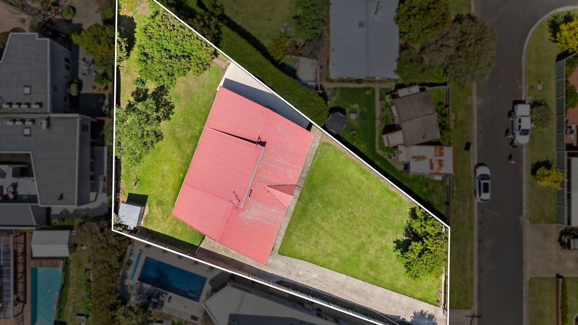 Vista aèria d'una propietat amb un edifici de gran mida amb teulada vermella, una piscina i vegetació als voltants.