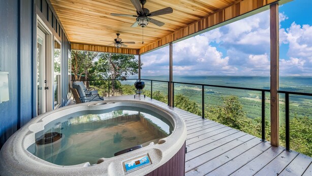 Un jacuzzi en una terraza de madera con vistas al paisaje.