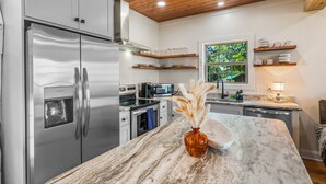 Una cocina moderna con electrodomésticos de acero inoxidable, encimera de mármol y vistas al exterior.