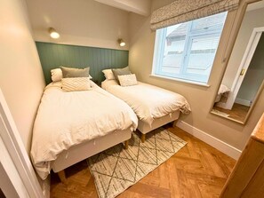 Une chambre avec deux lits, un tapis à motifs et une fenêtre avec des stores.