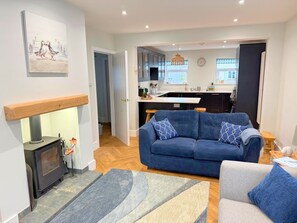 Un salon moderne avec un canapé, une cheminée et une cuisine en arrière-plan.