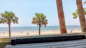 A beach view with palm trees and a wooden bench. - Charming BEACHFRONT condo in Galveston, 2 POOLS open year round, FITNESS CENTER (Galveston)