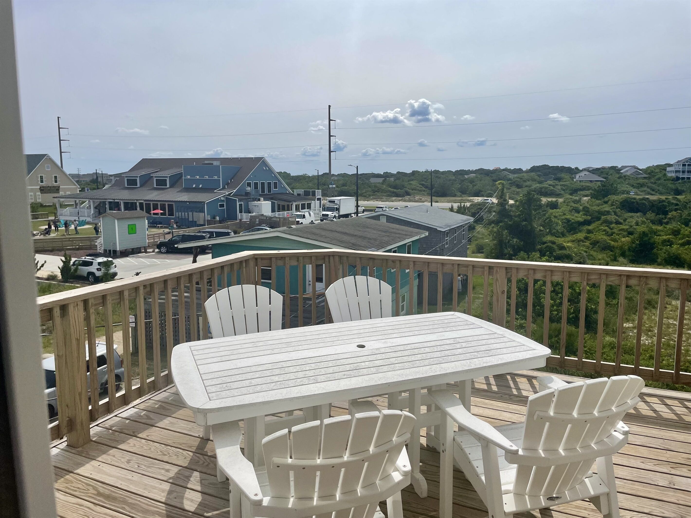Une terrasse avec une table et des chaises, donnant sur un quartier résidentiel avec des maisons et un parking.