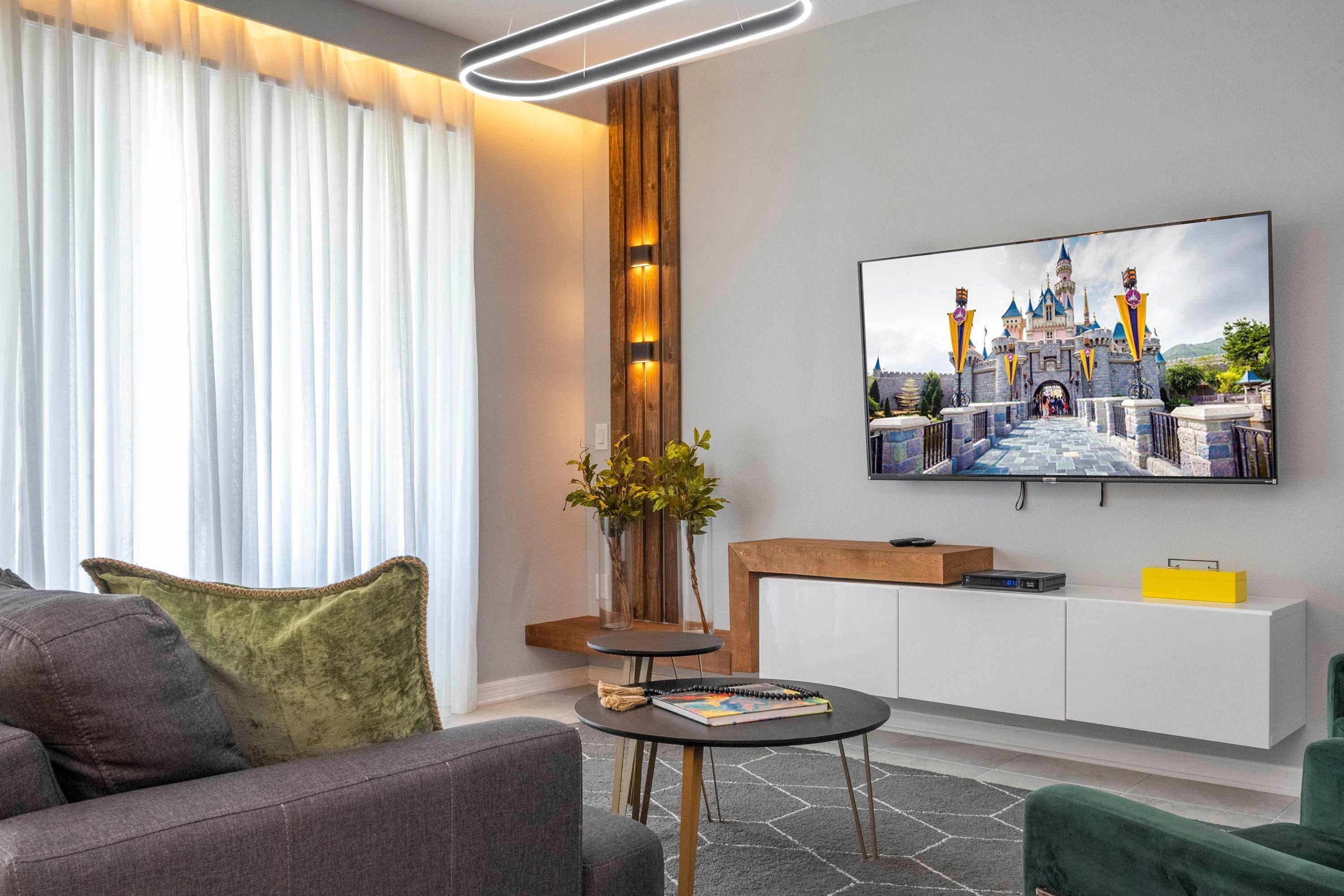 Una sala de estar moderna con un televisor de pantalla plana montado en la pared, un sofá, una mesa de centro y un aparador.