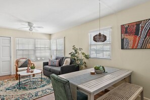 Una sala acogedora con un sofá, una mesa de comedor y un ventilador de techo.