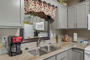 A kitchen with a double sink, a coffee maker, a microwave, and a decorative vase. - 1 BR | Whispering Pines | Indoor Pool | Mountain and D'town View (Pigeon Forge)