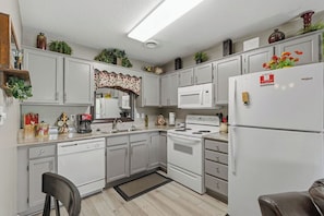 A kitchen with white cabinets, a microwave, a stove, and a refrigerator.