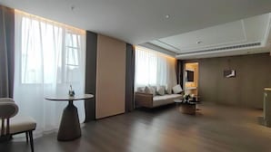Une chambre d’hôtel spacieuse, dotée d’un grand canapé, d’une table ronde et offrant une vue sur la ville.