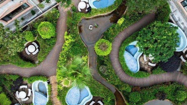 Vue aérienne d’un jardin aménagé, doté de plusieurs éléments aquatiques, de sentiers et d’espaces de repos.