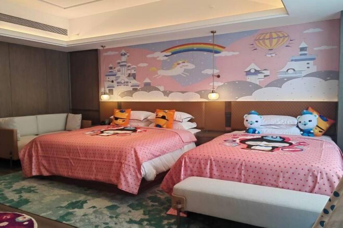 Habitación de hotel con dos camas, un mural en la pared y un pequeño banco.