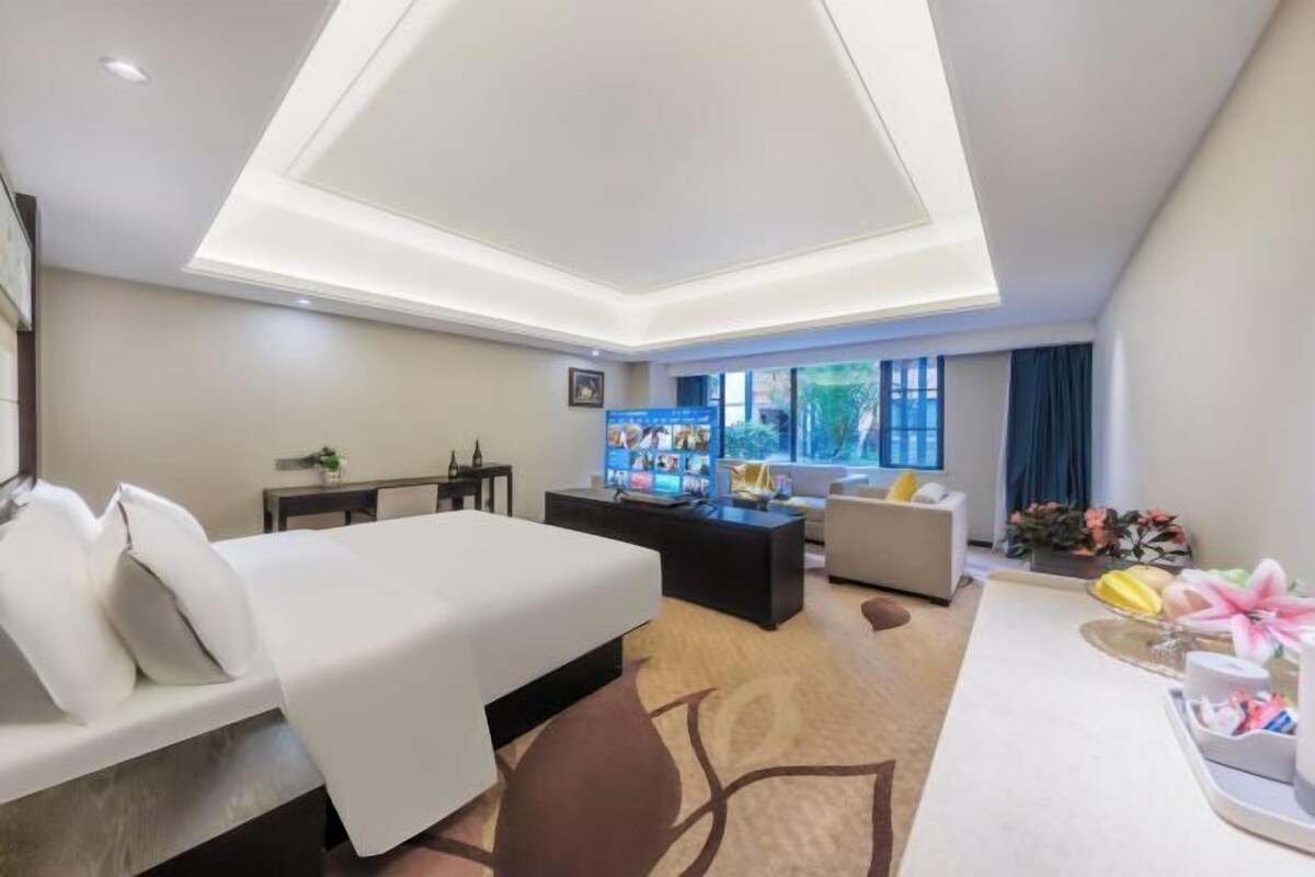 Une chambre d’hôtel équipée d’un lit, d’un bureau, d’un canapé, d’une télévision et d’une fenêtre avec des rideaux.