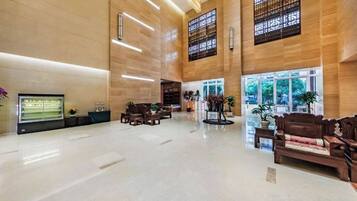 A spacious lobby with a high ceiling, large windows, and a reception desk.