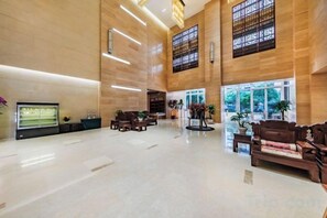 A spacious lobby with a high ceiling, large windows, and a reception desk.