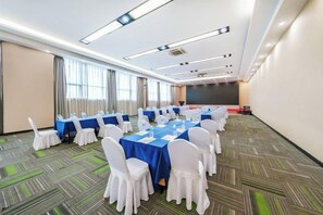 Ein Konferenzraum mit Tischen, Stühlen, einer Projektionsleinwand und Teppichboden.