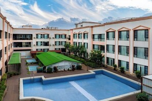 Ein Innenhof mit Schwimmbad, Tennisplatz und überdachter Sitzgelegenheit.