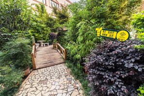 Ein gepflasterter Weg führt zu einer Holzbrücke in einem üppigen Garten.