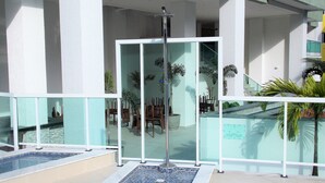 A modern outdoor pool area with a glass enclosure, seating, and potted plants. - Apartment Praia Grande Ubatuba | REF KC04H (Ubatuba)
