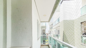 Un pasillo estrecho con una pared de hormigón a un lado y un balcón de cristal al otro.