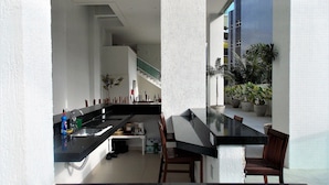 Una cocina moderna con encimera negra, sillas de madera y una escalera que sube a un nivel superior.