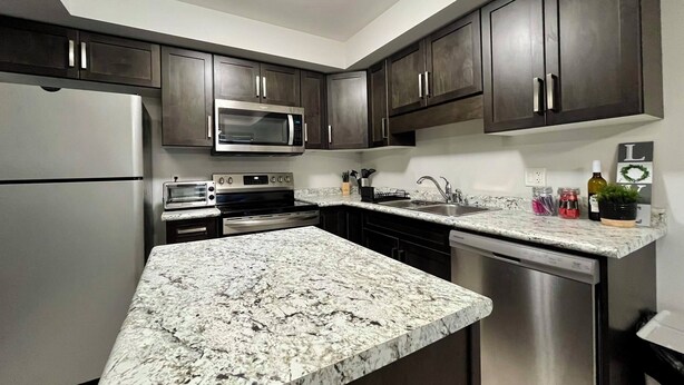 A modern kitchen with dark wood cabinets, stainless steel appliances, and a granite countertop. - Niagara Getaway 
4bdrm, 4bths. 18 min to Falls.
'Isla Paraiso Verde' (Thorold)