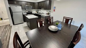 A modern kitchen with dark cabinets, stainless steel appliances, and a dining area with a wooden table and chairs. - Niagara Getaway 
4bdrm, 4bths. 18 min to Falls.
'Isla Paraiso Verde' (Thorold)