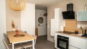 A modern kitchen with a dining area, featuring a wooden table, chairs, a built-in oven, and a TV mounted above the counter.