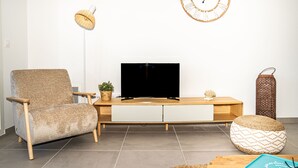 A living room with a sofa, a TV, a wooden coffee table, a clock, a floor lamp, and a decorative basket.