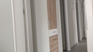 Un couloir avec des portes blanches et une armoire dotée d’un panneau en bois.