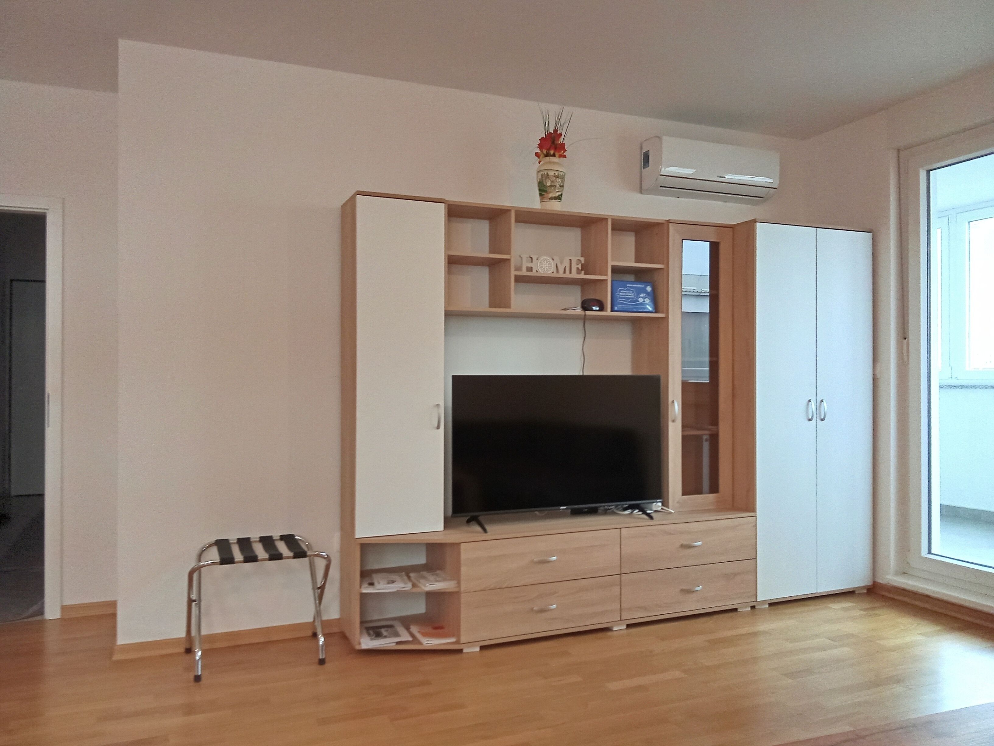 Una habitación con un mueble de entretenimiento de madera, un televisor y un armario.