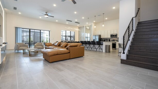 A spacious living area with a large sofa, a dining table, and a kitchen in the background. - Last Minute Disney! Private Pool, Hot Tub & Themed Bedrooms. Book Now! #119687 (Orlando)