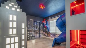 A room with a cityscape mural, a Spiderman statue, a blue slide, and a neon Spiderman sign. - Last Minute Disney! Private Pool, Hot Tub & Themed Bedrooms. Book Now! #119687 (Orlando)