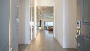A modern hallway with a marble wall, a glass door, and a view into a living area with a sofa and a coffee table. - Last Minute Disney! Private Pool, Hot Tub & Themed Bedrooms. Book Now! #119687 (Orlando)