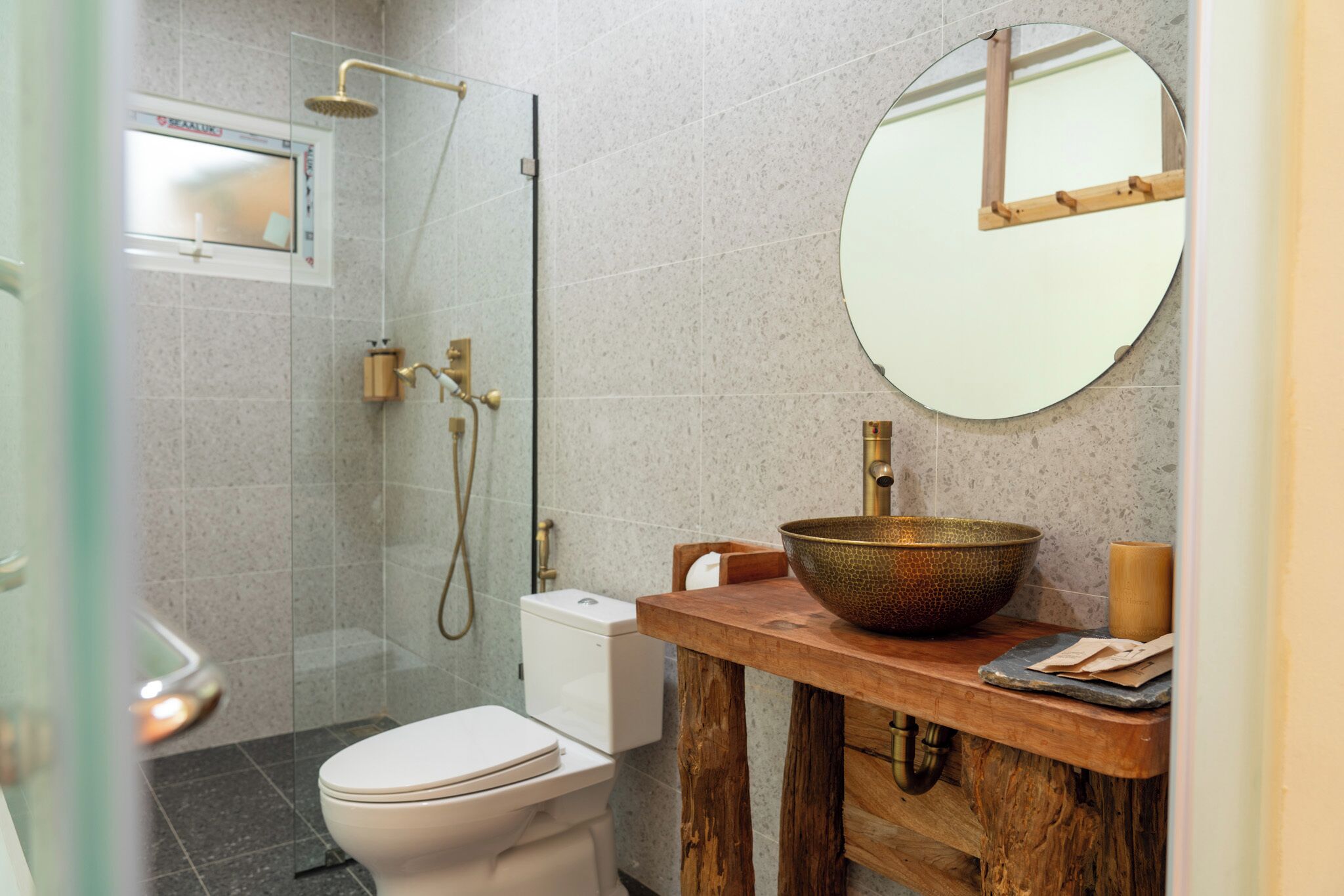 Un baño moderno con cabina de ducha de vidrio, inodoro blanco y tocador de madera con un lavamanos grande.