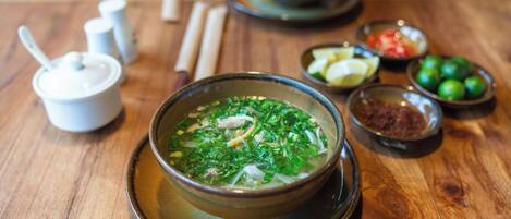 Una mesa con un tazón de sopa, salsas y una cuchara.