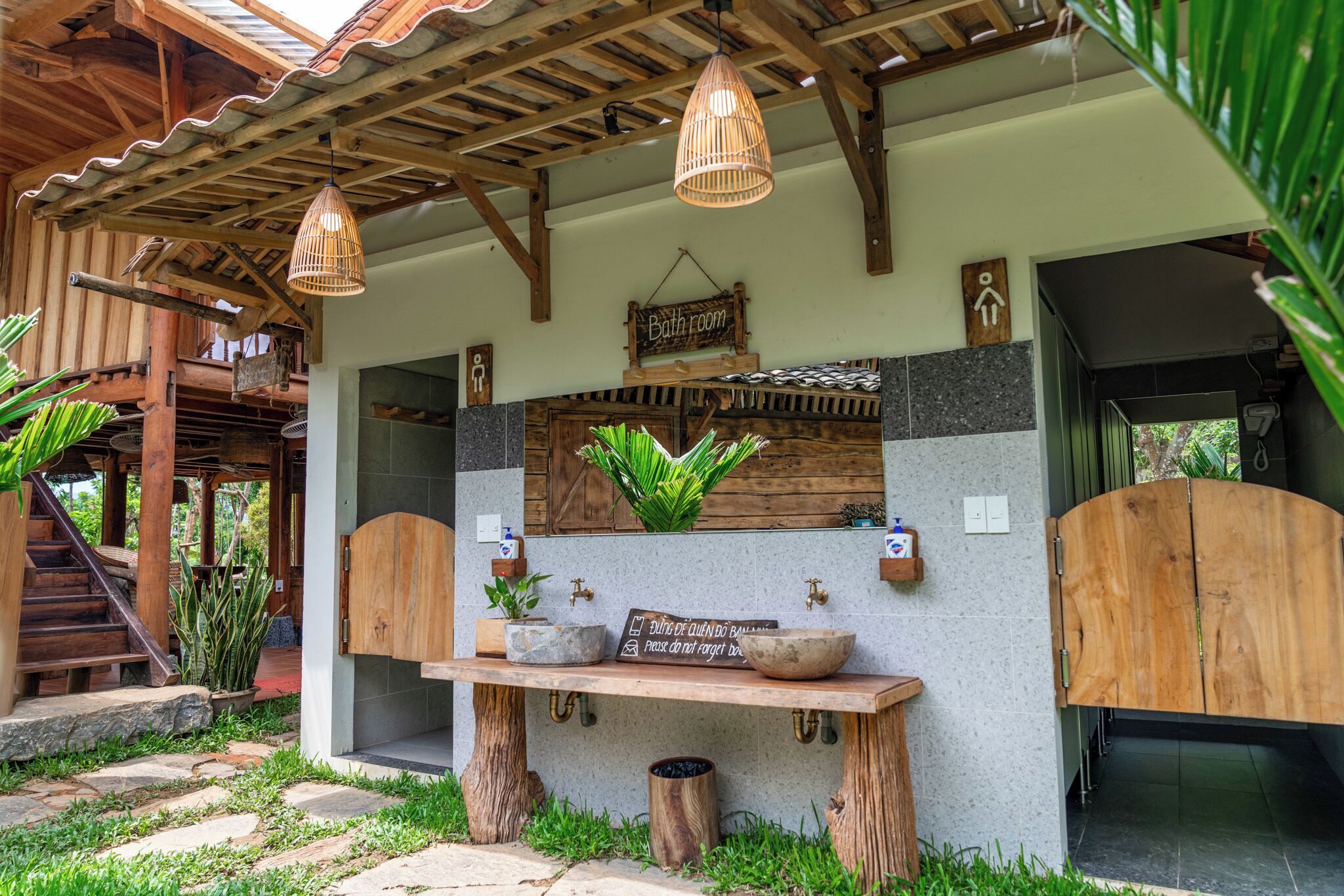 A rustic bathroom with a wooden sink, two hanging light fixtures, and a sign indicating the bathroom's location.