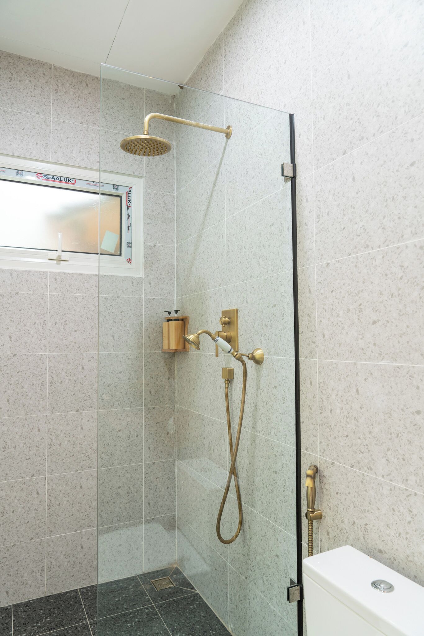 Eine Duschkabine mit Handbrause und am Wand montiertem Wasserhahn.