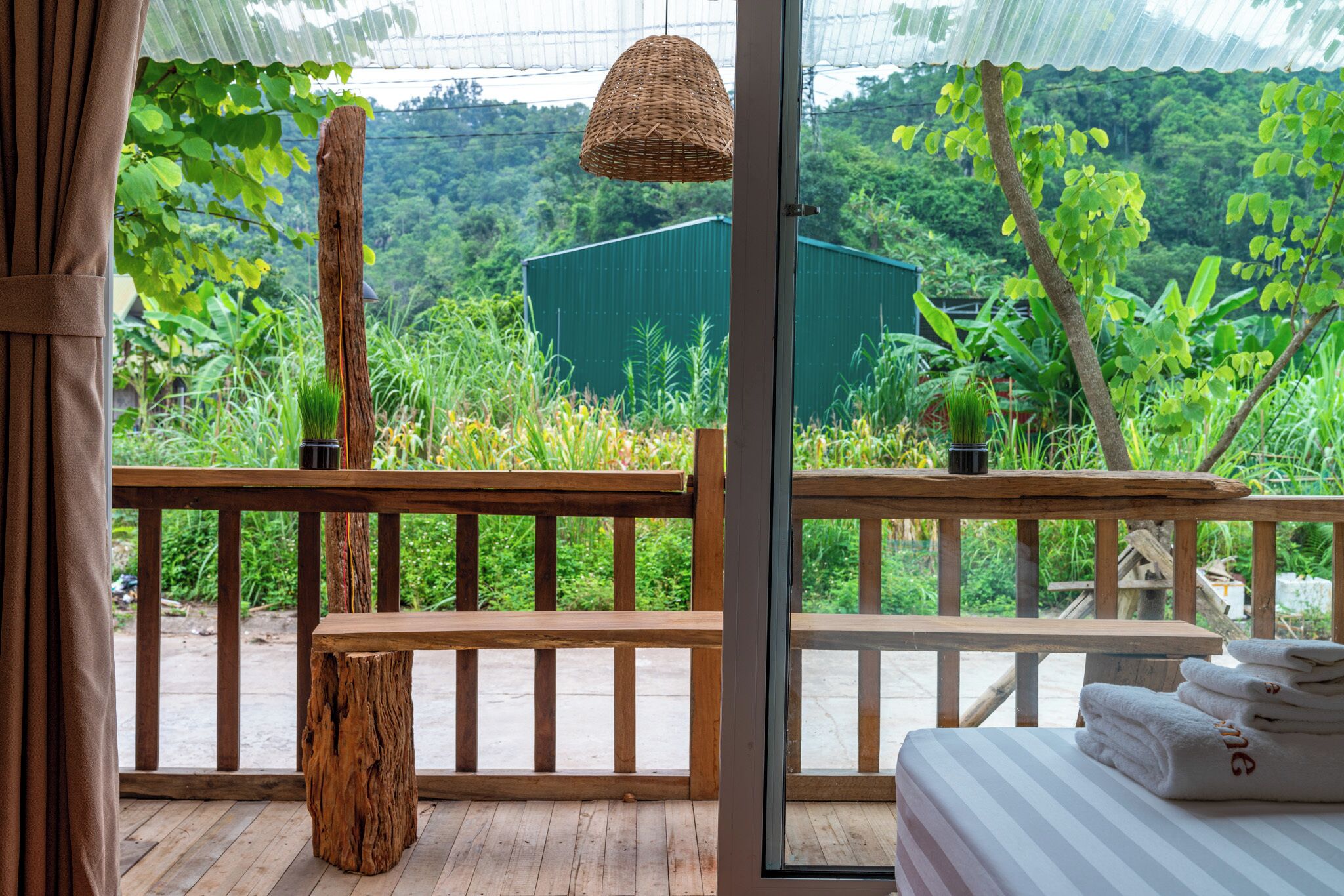 Una terraza de madera con un banco, una mesa y una cama con toallas.