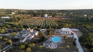 Vue aérienne d’une propriété comprenant plusieurs bâtiments, une piscine et un vignoble.