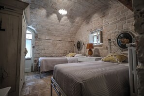 A bedroom with two beds, stone walls, a window, and a door. - La Casedda don Gaetano: nature and pool in the trulli village (Monopoli)