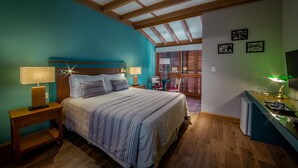 A bedroom with a bed, bedside tables, a desk with a chair, a window, and a balcony. - Hotel Boutique Britânico (Gramado)