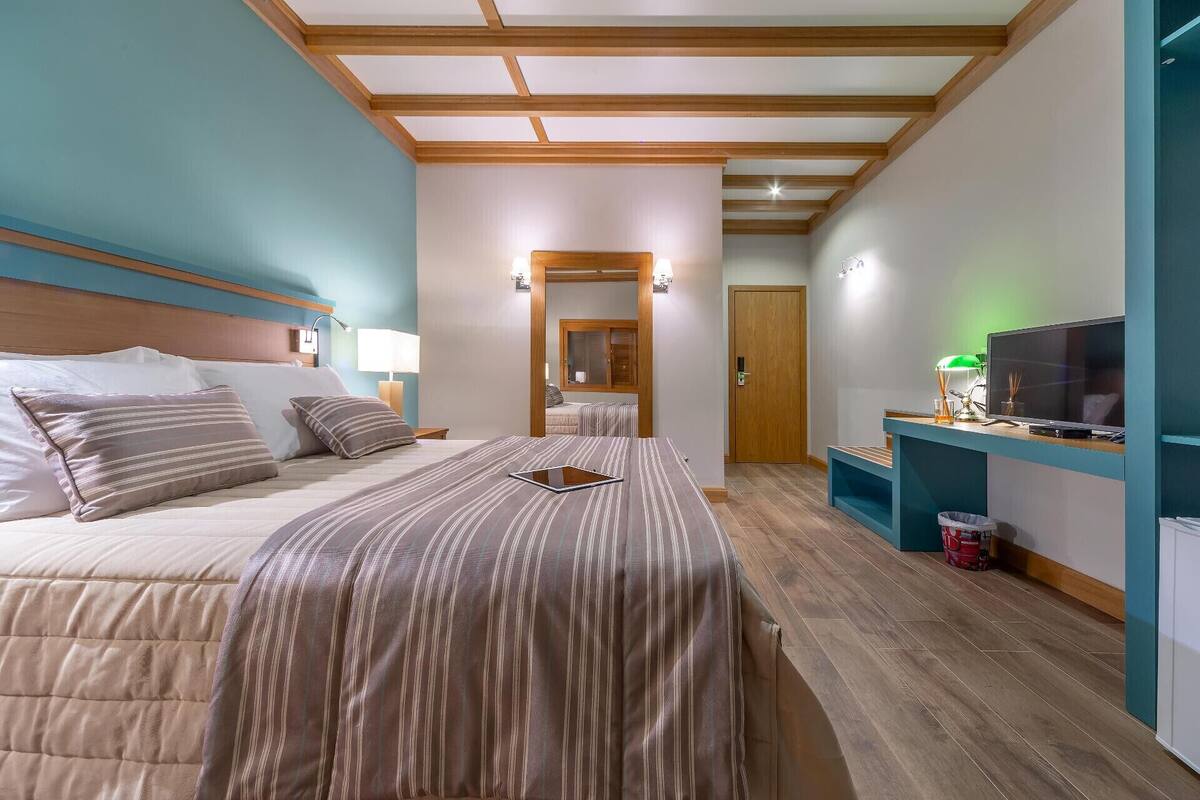 A hotel room with a large bed, a desk with a TV, and a bathroom visible through an open door.